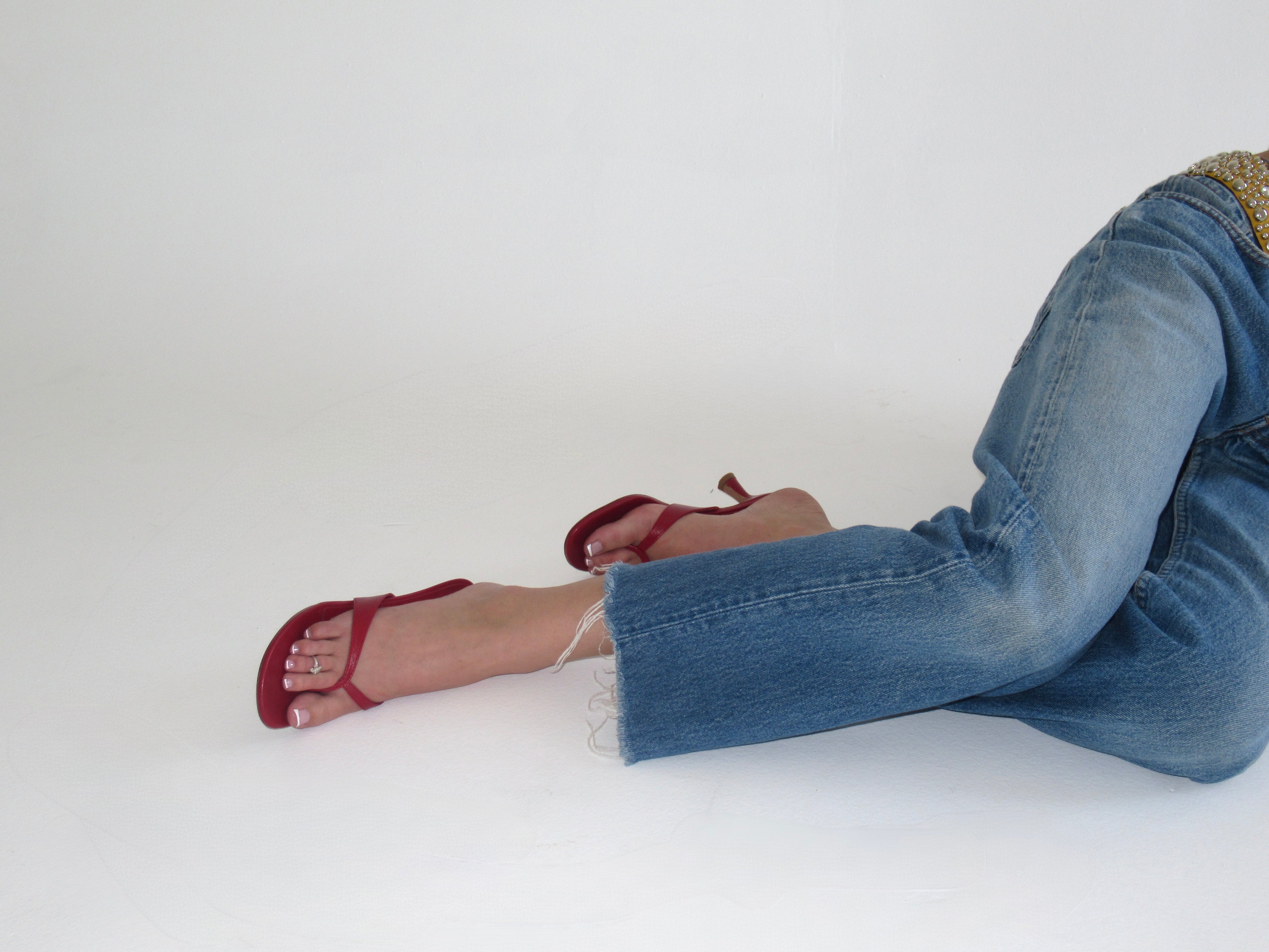 Person wearing blue jeans and red high-heeled shoes on a white background