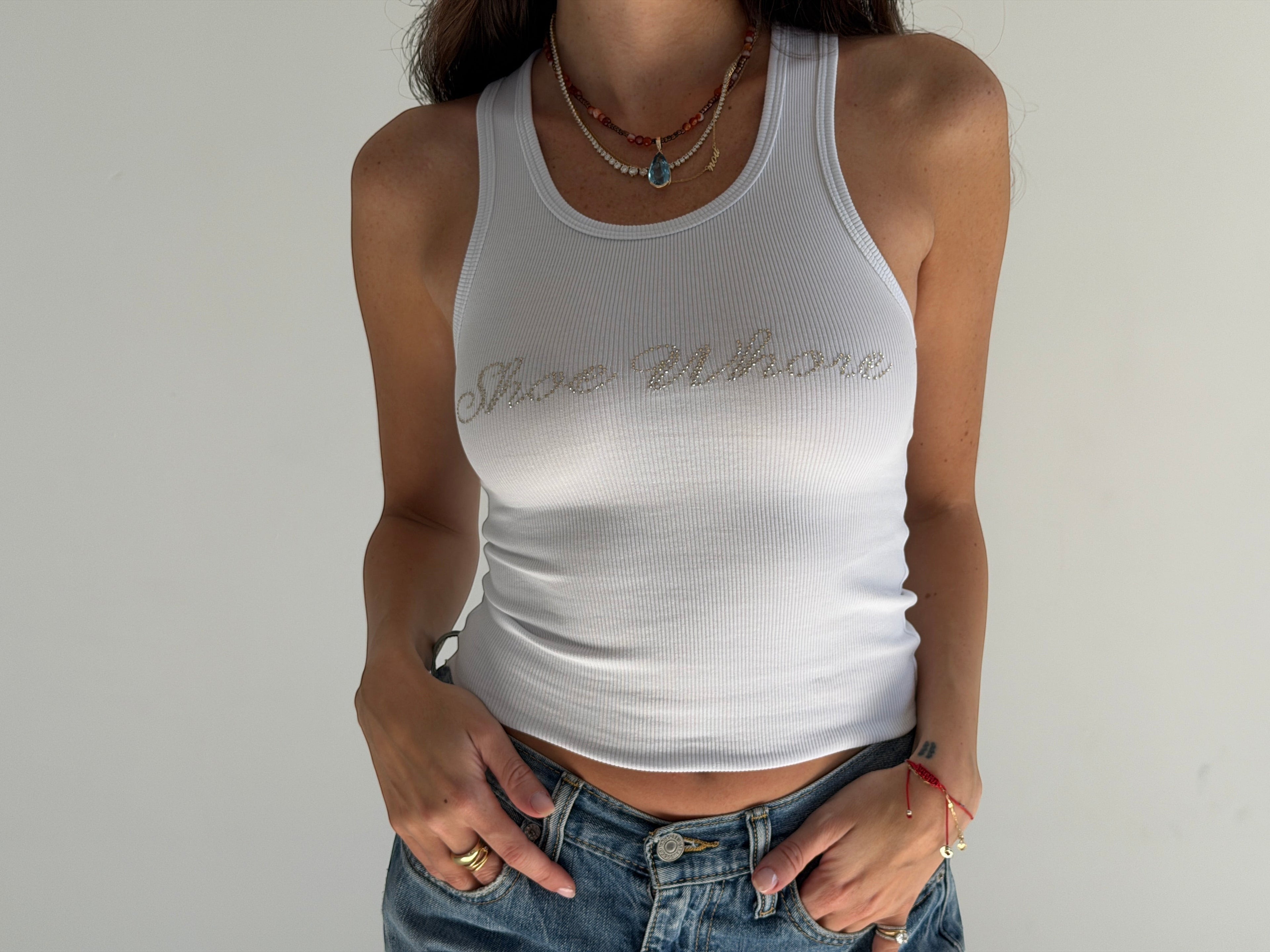 Person wearing a white tank top with text on a plain background