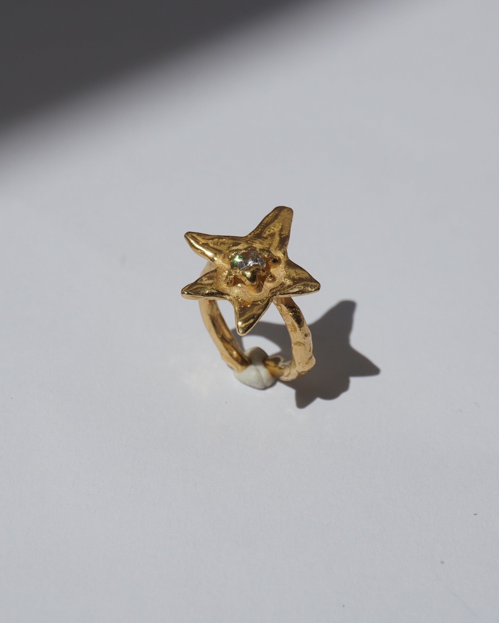 NOU Astra toe ring in 24K gold-plated sterling silver with a star-shaped design and a small central gemstone.