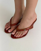 NOU The Puff Wedge in blood orange snakeskin with a 3-inch sculptural heel and gold logo detail.