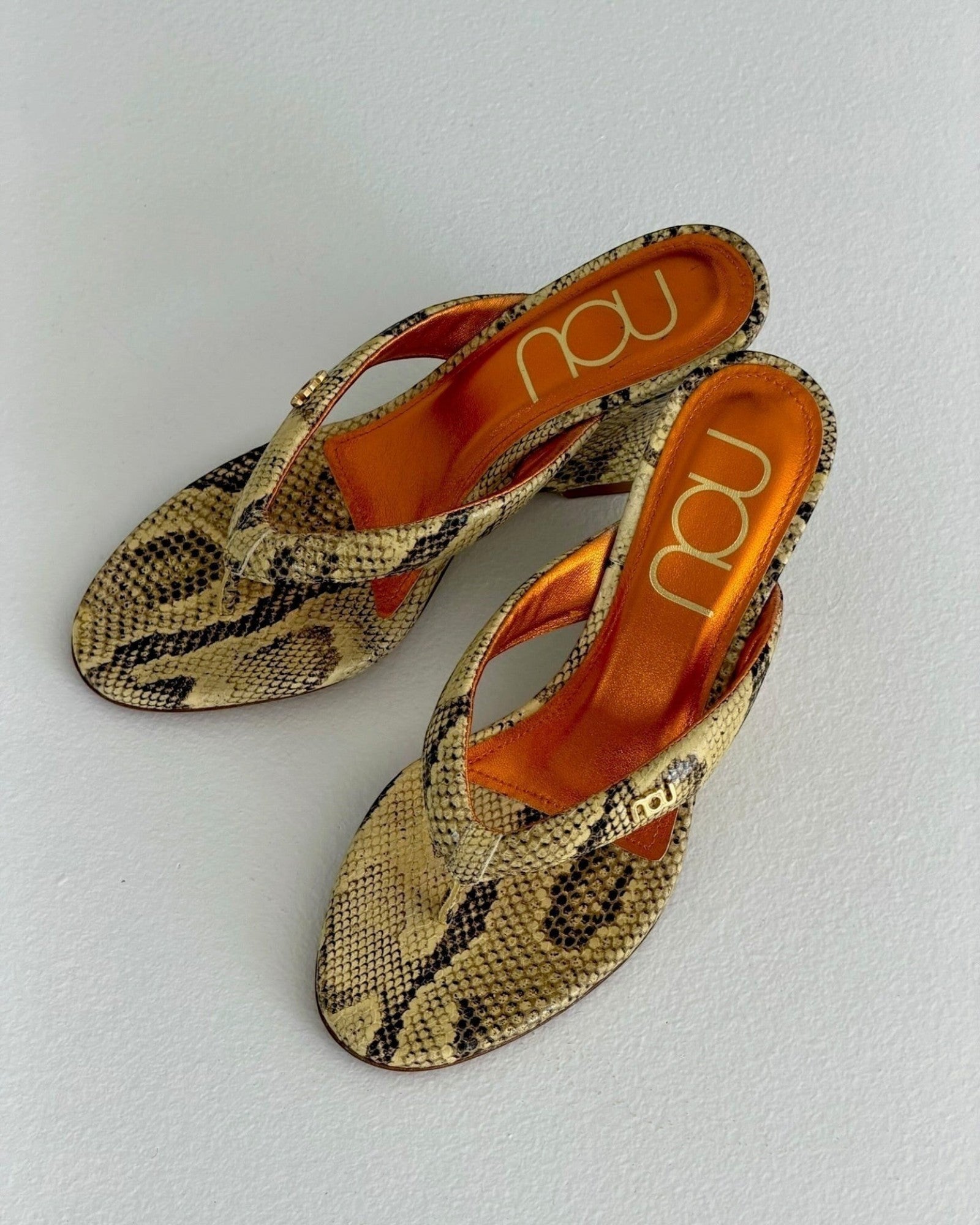 NOU The Puff Wedge in Creamsicle python snakeskin finish with a 3-inch sculptural heel and metallic orange insole.