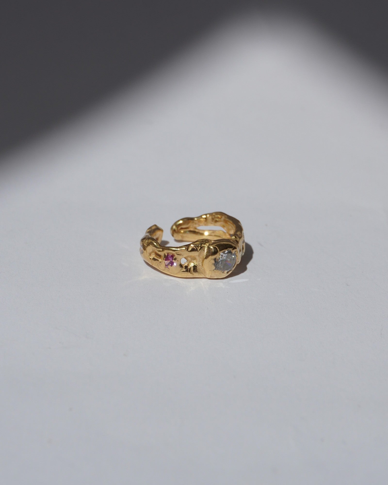 NOU Sirena adjustable toe ring in 24K gold-plated sterling silver with small gemstone accents on a white surface.