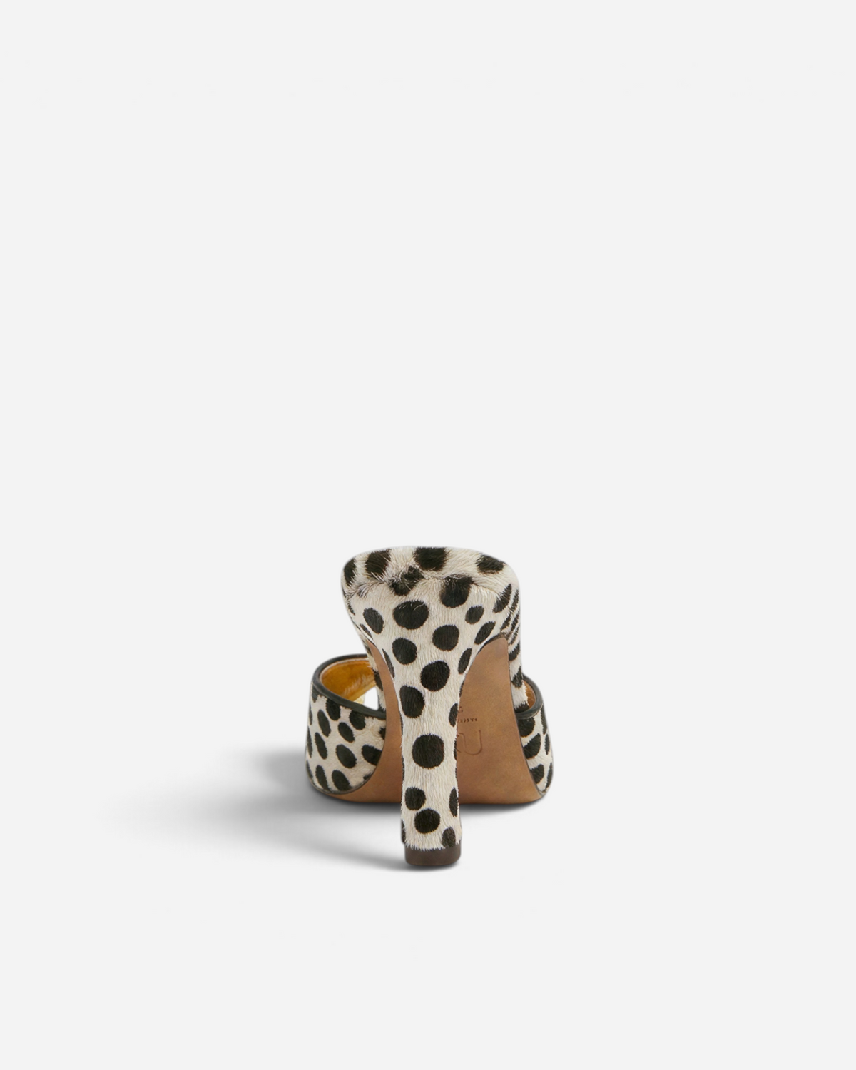 NOU The Mule in dalmatian print ponyhair with a metallic gold insole, shown from a rear heel view.