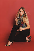 Model wearing NOU The Pump heels in camo ponyhair with metallic pink insoles, styled with a floral vest and trousers.